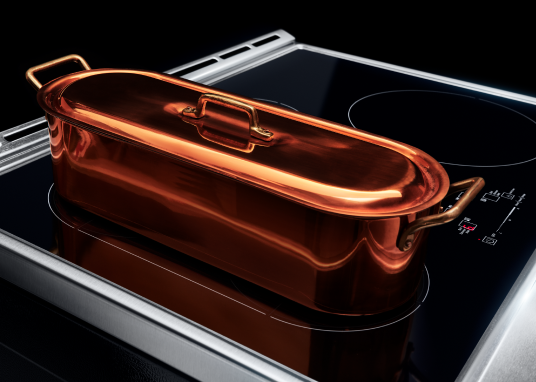 Specialty induction cookware placed on top of an induction cooktop with multiple cooking zones.