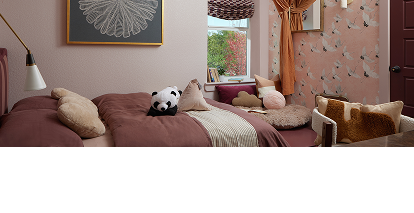 A bright bedroom with a plush panda and other pillows on the bed.
