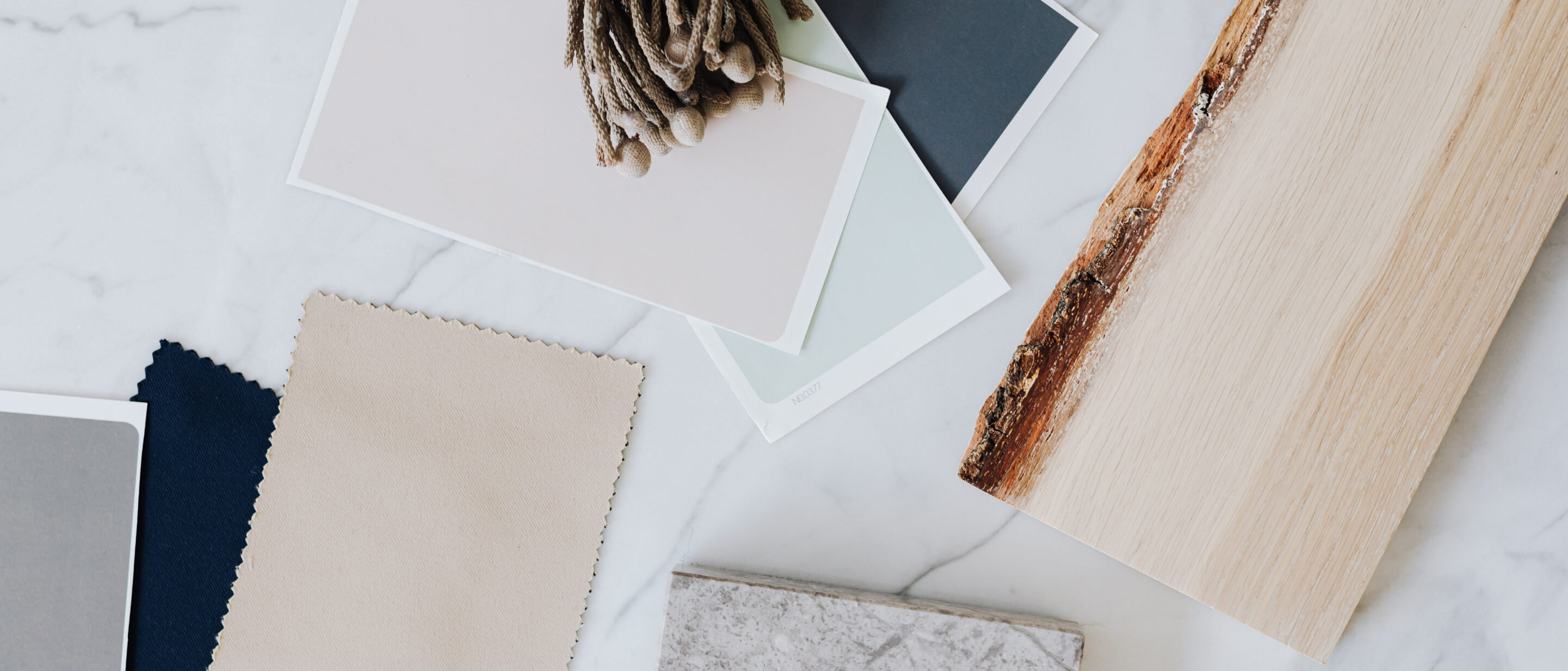 A series of swatches of soft colors, including beige, layered with wood, stone and other natural materials to form a pallet.
