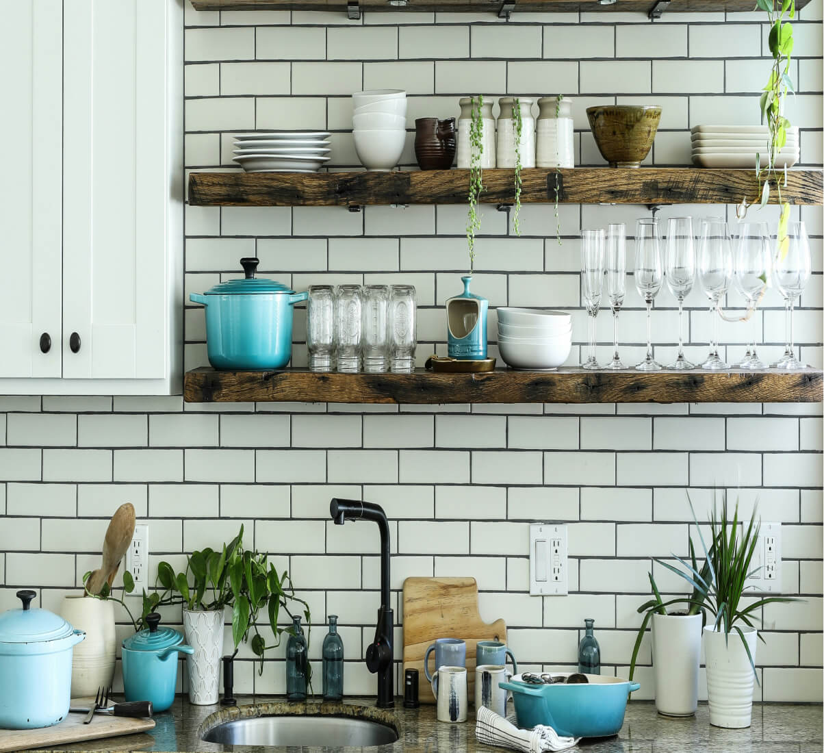 A close-up of a white subway tile kitchen with open shelving.