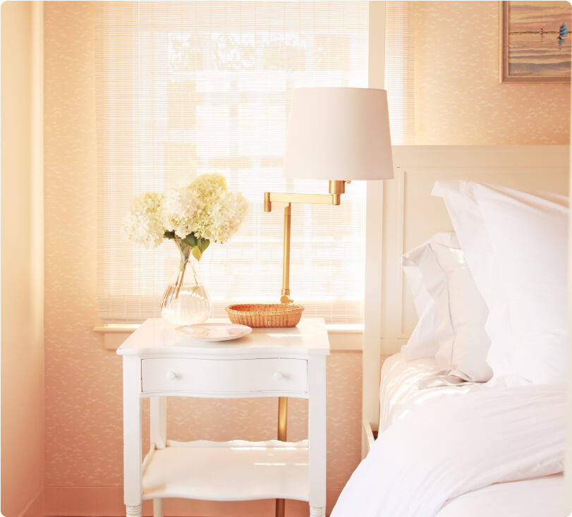 The nightstand decorated with hydrangeas and other dishes next to the bed. 