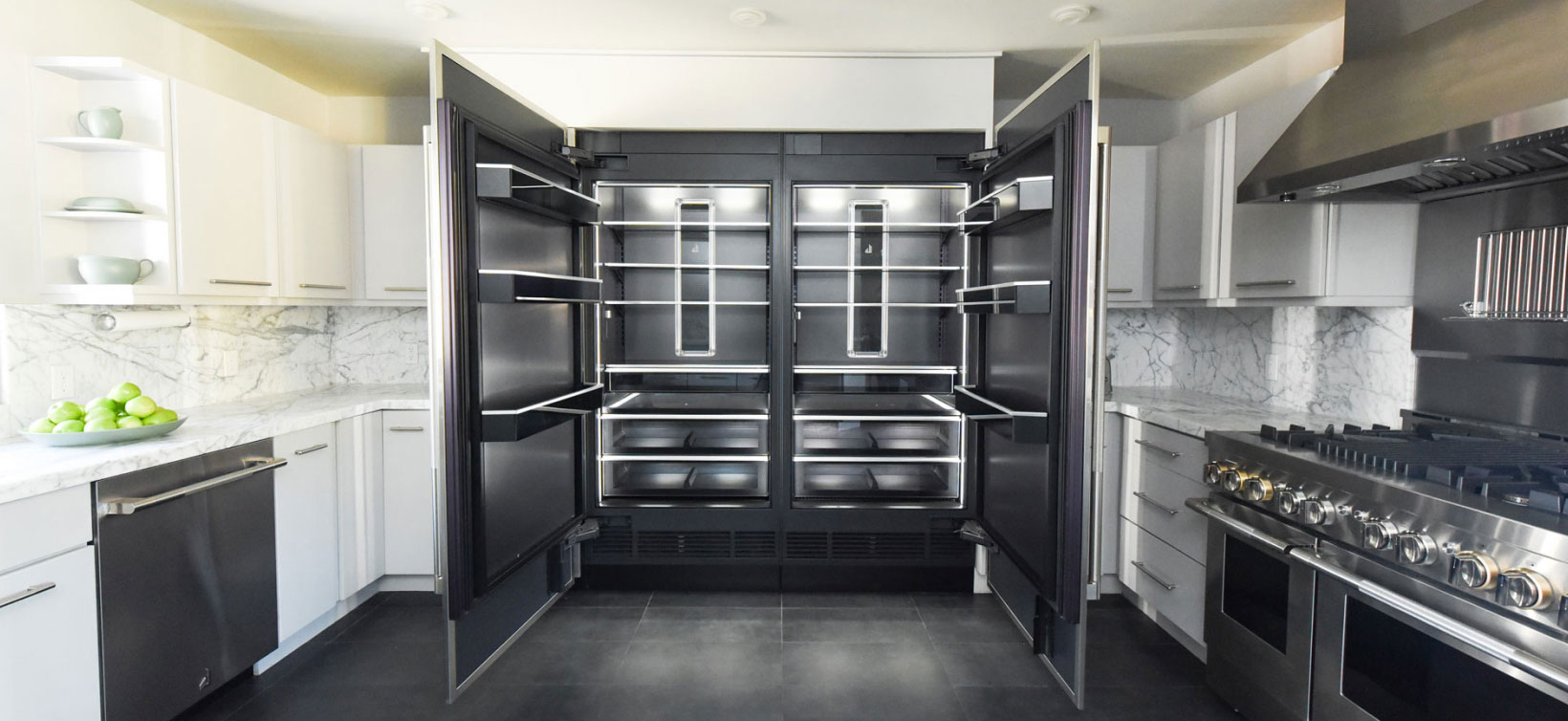 A bold, modern kitchen with an open JennAir® Refrigerator showcasing the Daring Obsidian Interior.