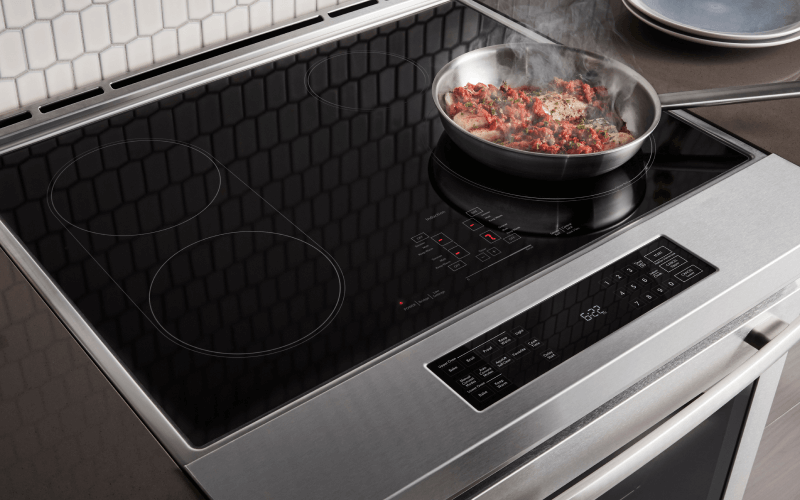 Fresh ingredients being cooked on an induction cooktop on a range.