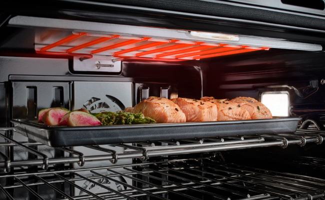 Salmon, asparagus and other vegetables cooking in a JennAir Wall Oven. 