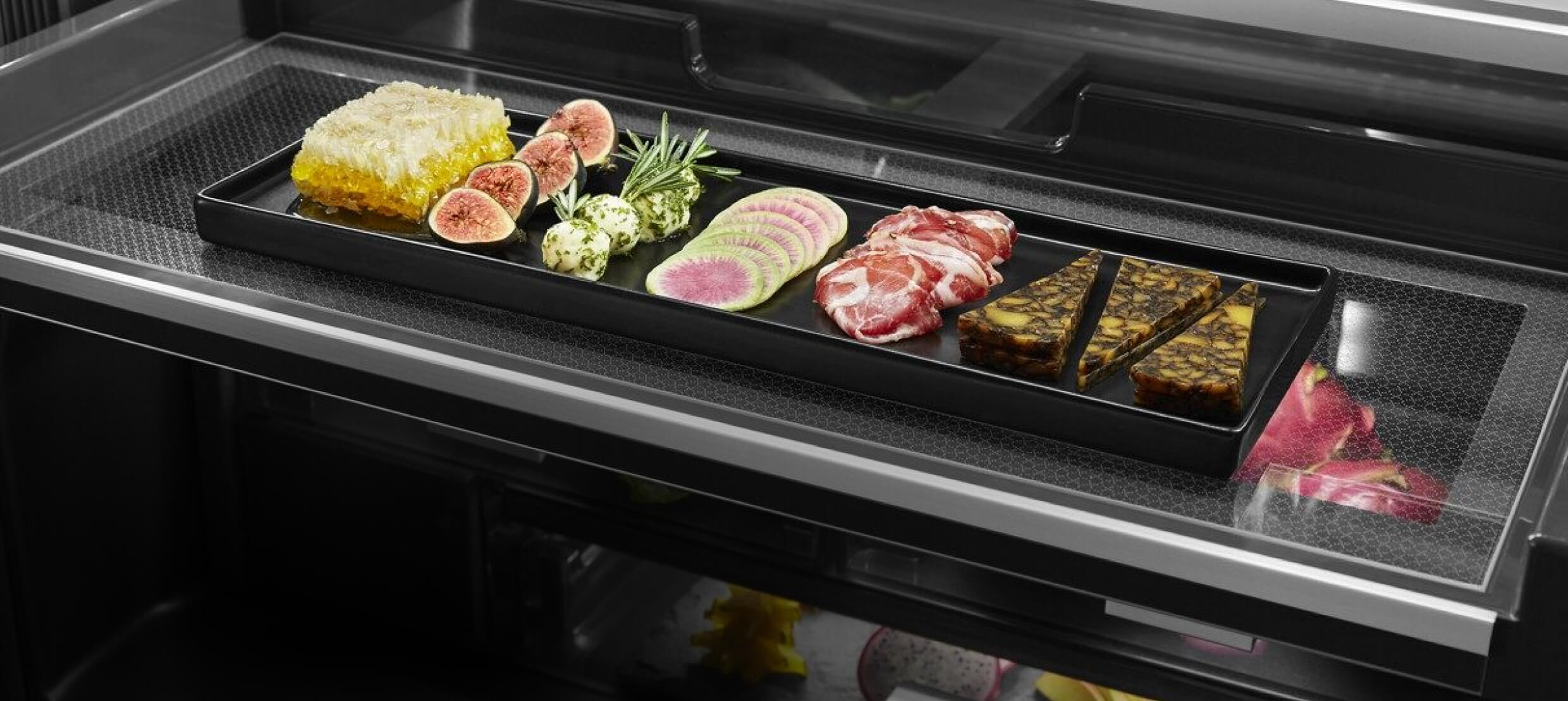 An open drawer showcasing fine ingredients in a freestanding refrigerator. 