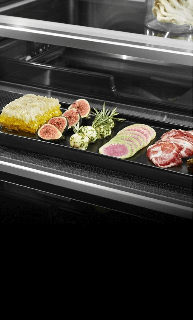 An open drawer showcasing fine ingredients in a freestanding refrigerator. 