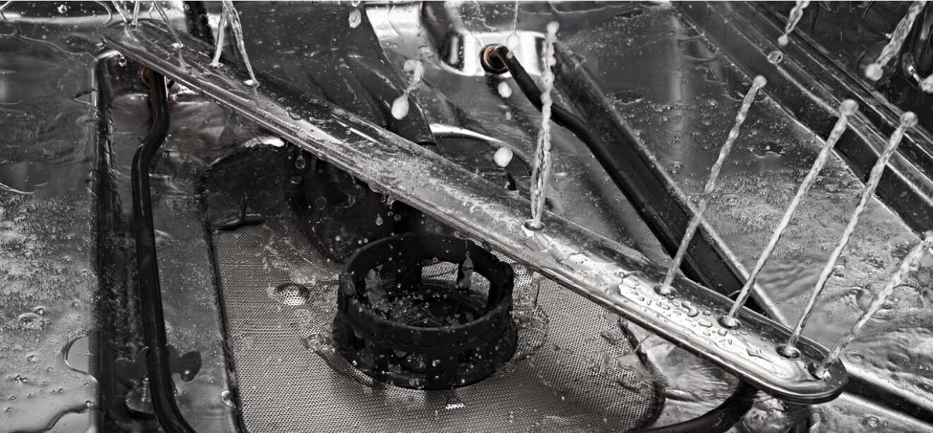 The interior of a JennAir® dishwasher, water spraying from the spray arms.